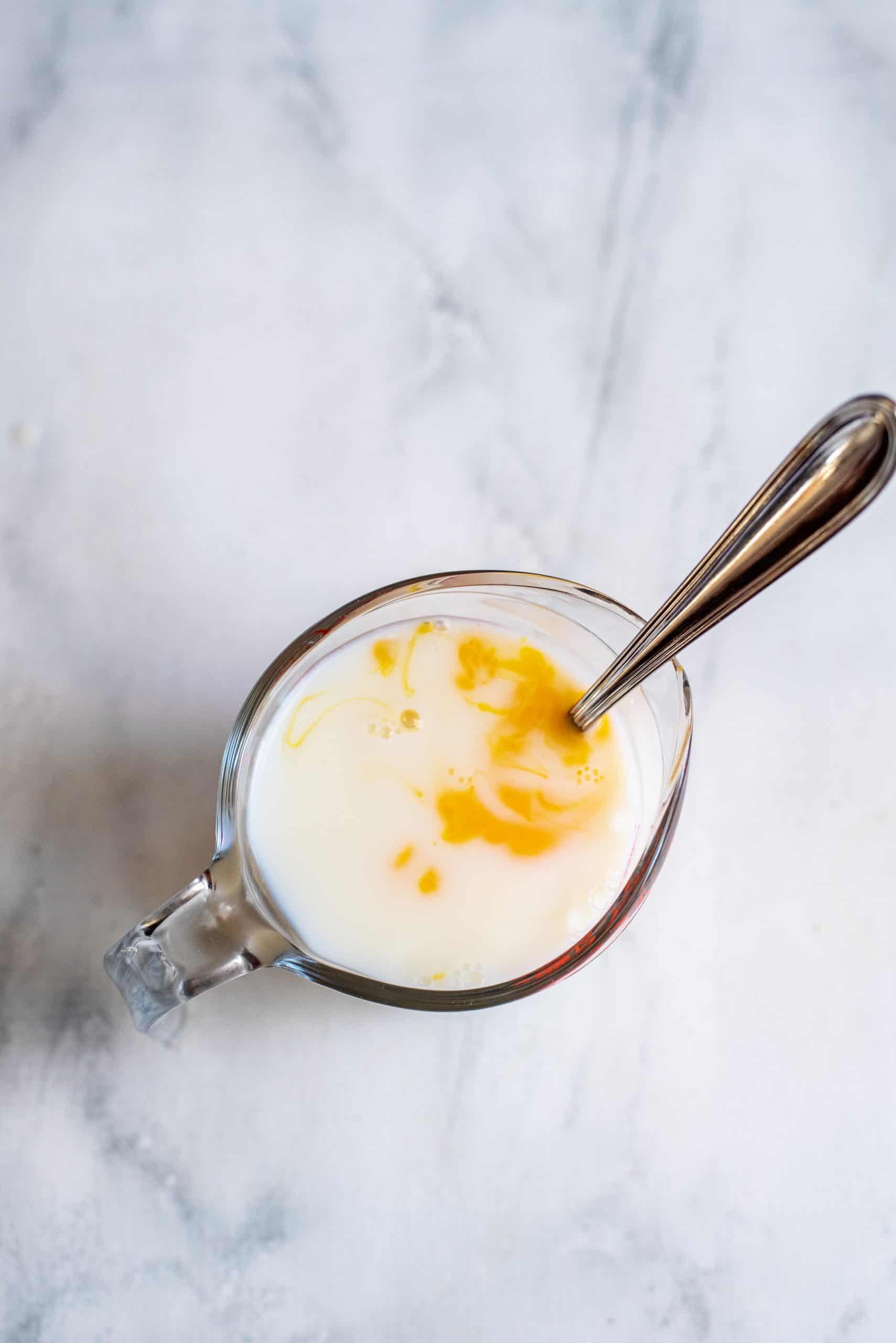 Beating together milk and eggs in separate measuring cup.