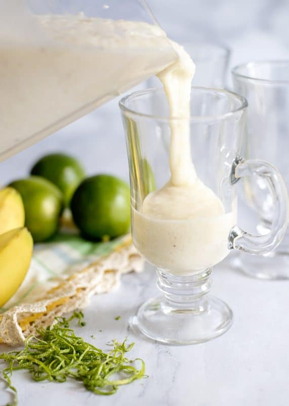 Pouring banana smoothie into glass.