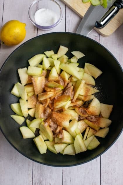 Sautéed apples with cinnamon sugar cooking in a skillet.