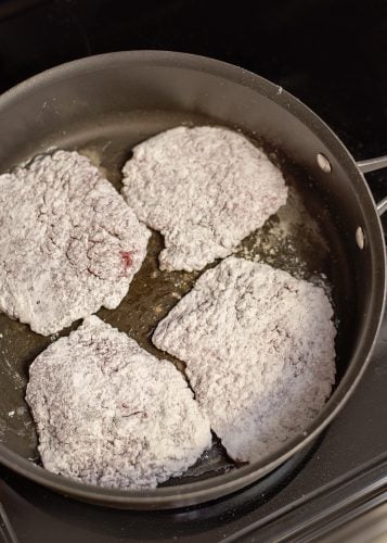 Frying breaded cubed steaks.