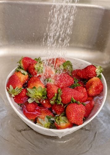 Washing strawberries in sink.