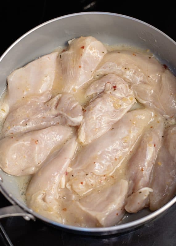 Chicken tenders grilling on stovetop.