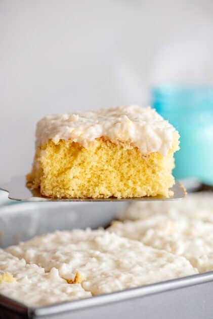 Slice of coconut poke cake on spatula.