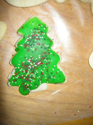 Christmas tree cutout cookie with green icing and sprinkles.