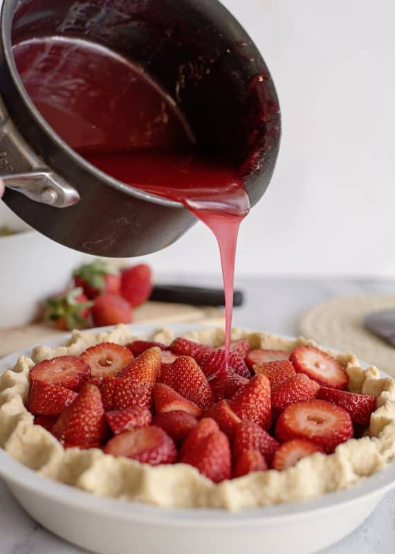 Pouring Glaze over Strawberries for Fresh Strawberry Pie