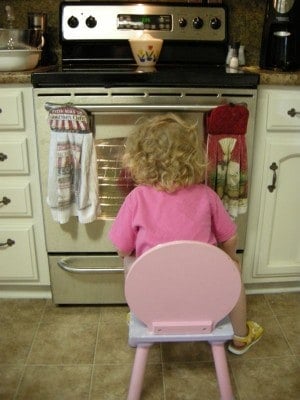 Daughter watching cake cook in oven.