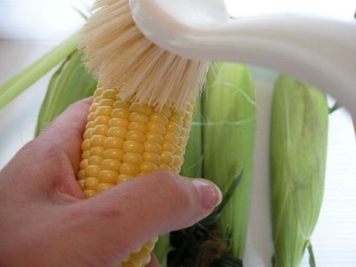 Silk the corn using a stiff brush.