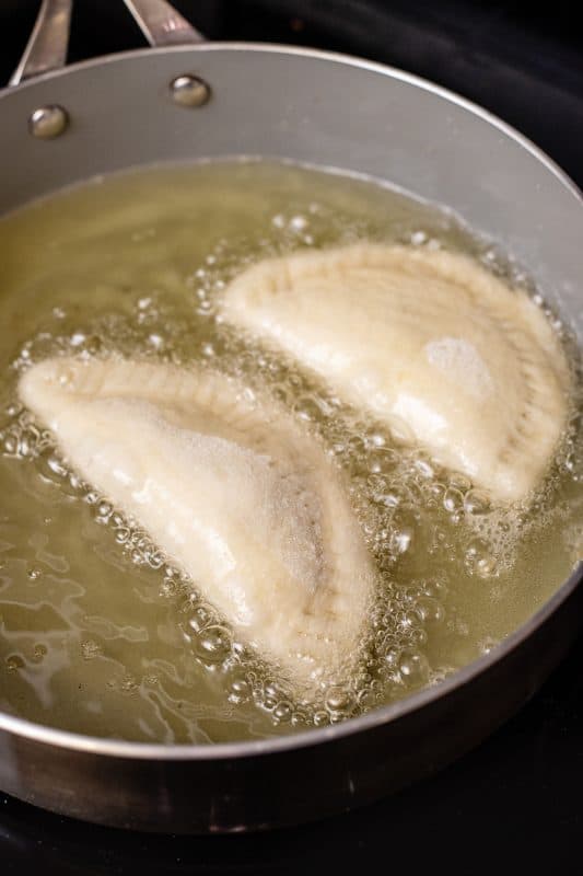 Frying pies in a skillet filled with oil.