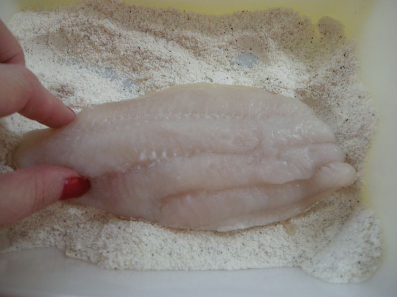 Dipping catfish in cornmeal mixture.