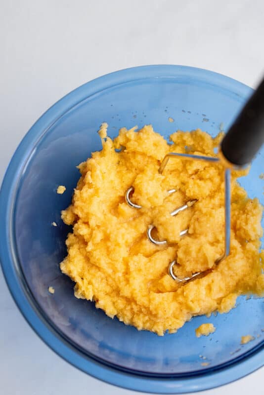 Mashing peaches with potato masher.