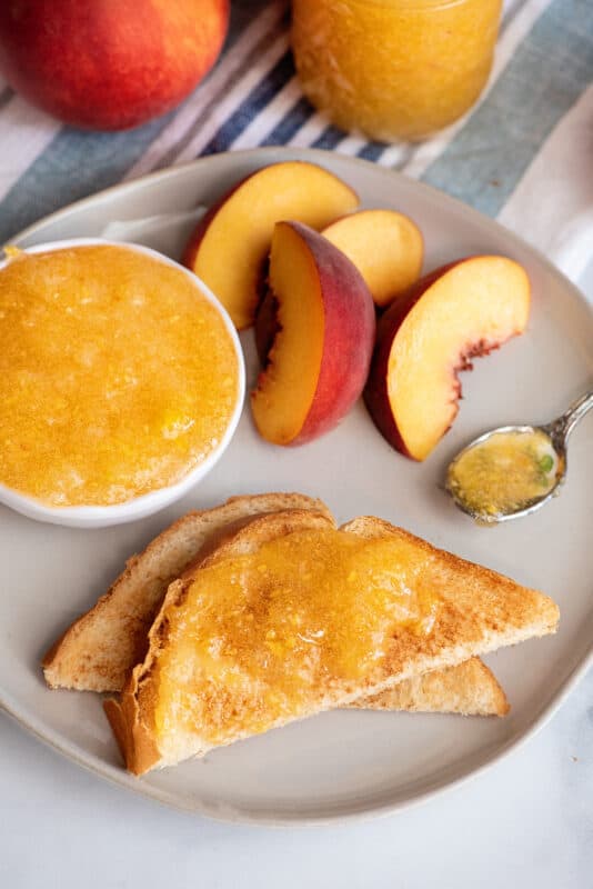 Peach jam on toast with peach slices on plate.