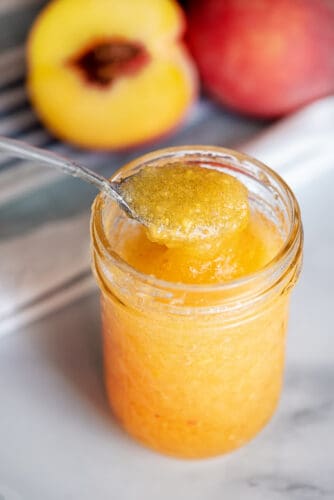 Scoop of peach freezer jam from jar.