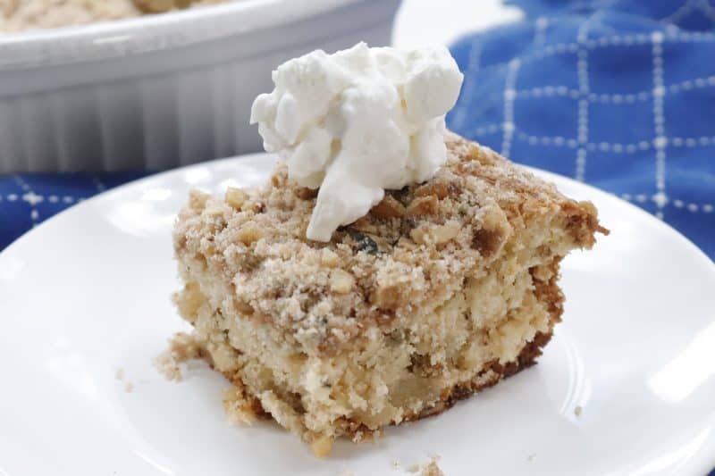 Slice of apple crumble cake with whipped cream.