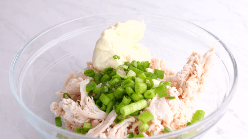 Shredded chicken, green onions and mayo in mixing bowl.