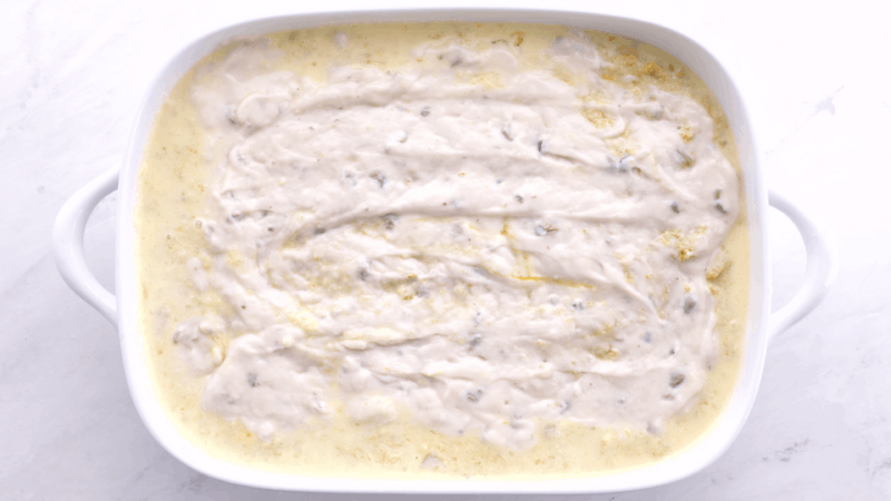 Cream of mushroom soup spread over chicken poulet in pan.
