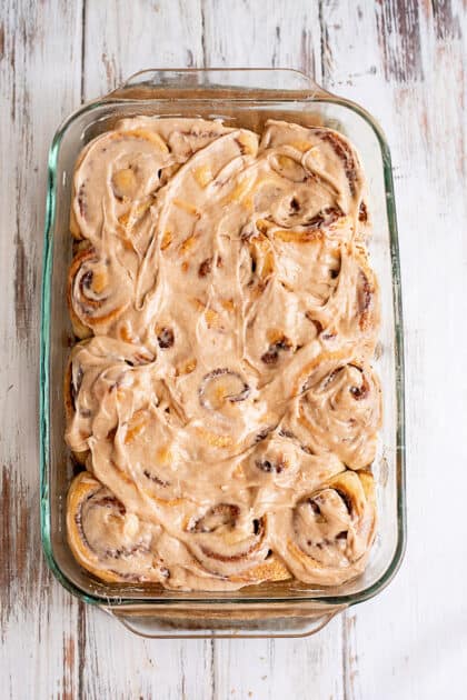 Spread icing over homemade cinnamon rolls.