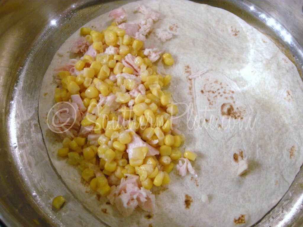 Chicken and corn sprinkled over a flour tortilla in a skillet