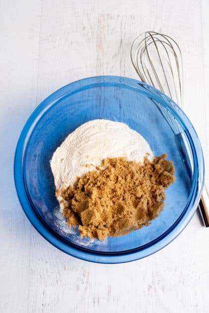Brown sugar and flour in a glass blue mixing bowl.