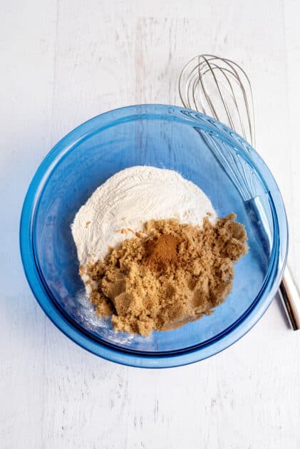 Cinnamon, brown sugar, and flour in a glass blue mixing bowl.