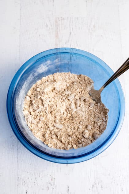 Dry ingredients for peach cobbler muffins with a fork.