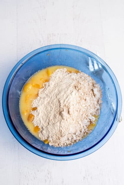 Combining the dry ingredients to the wet ingredients in a glass blue mixing bowl.