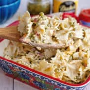 A serving dish of Velveeta bowtie pasta with a wooden spoon scooping some out.