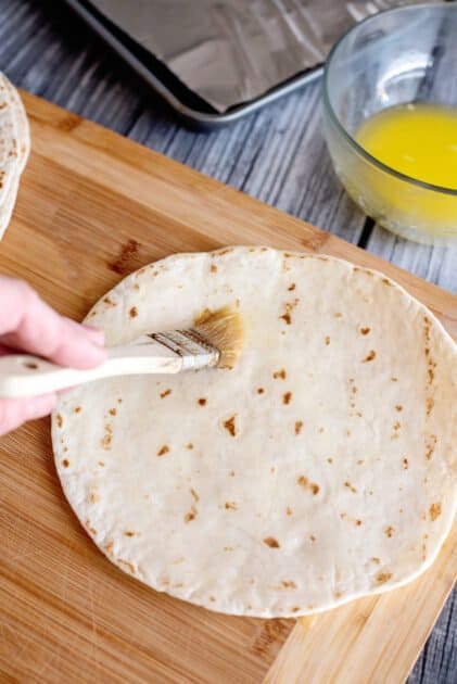 Brush one side of tortilla with butter.