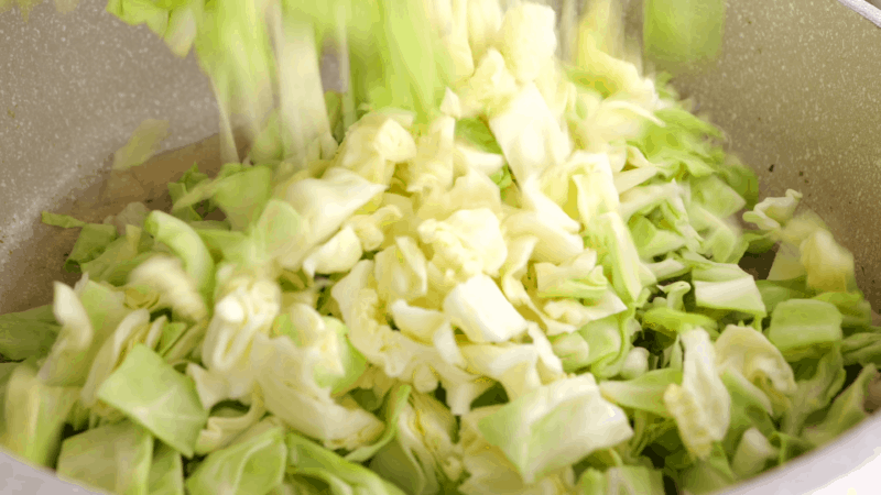 Tossing cabbage into skillet.