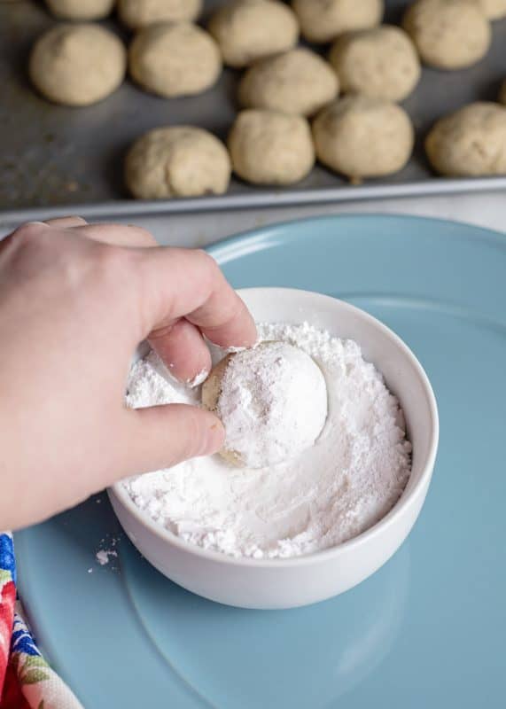 Rolling baked cookies in confectioner's sugar.