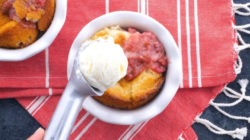 Adding scoop of ice cream to homemade strawberry cobbler.