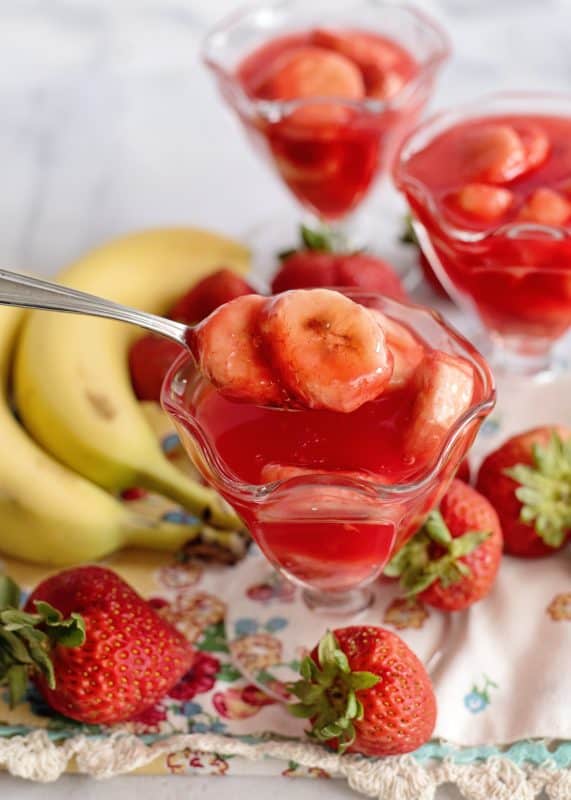 Spoonful of bananas in strawberry glaze.