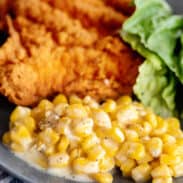 Creamed corn with fried chicken on plate.