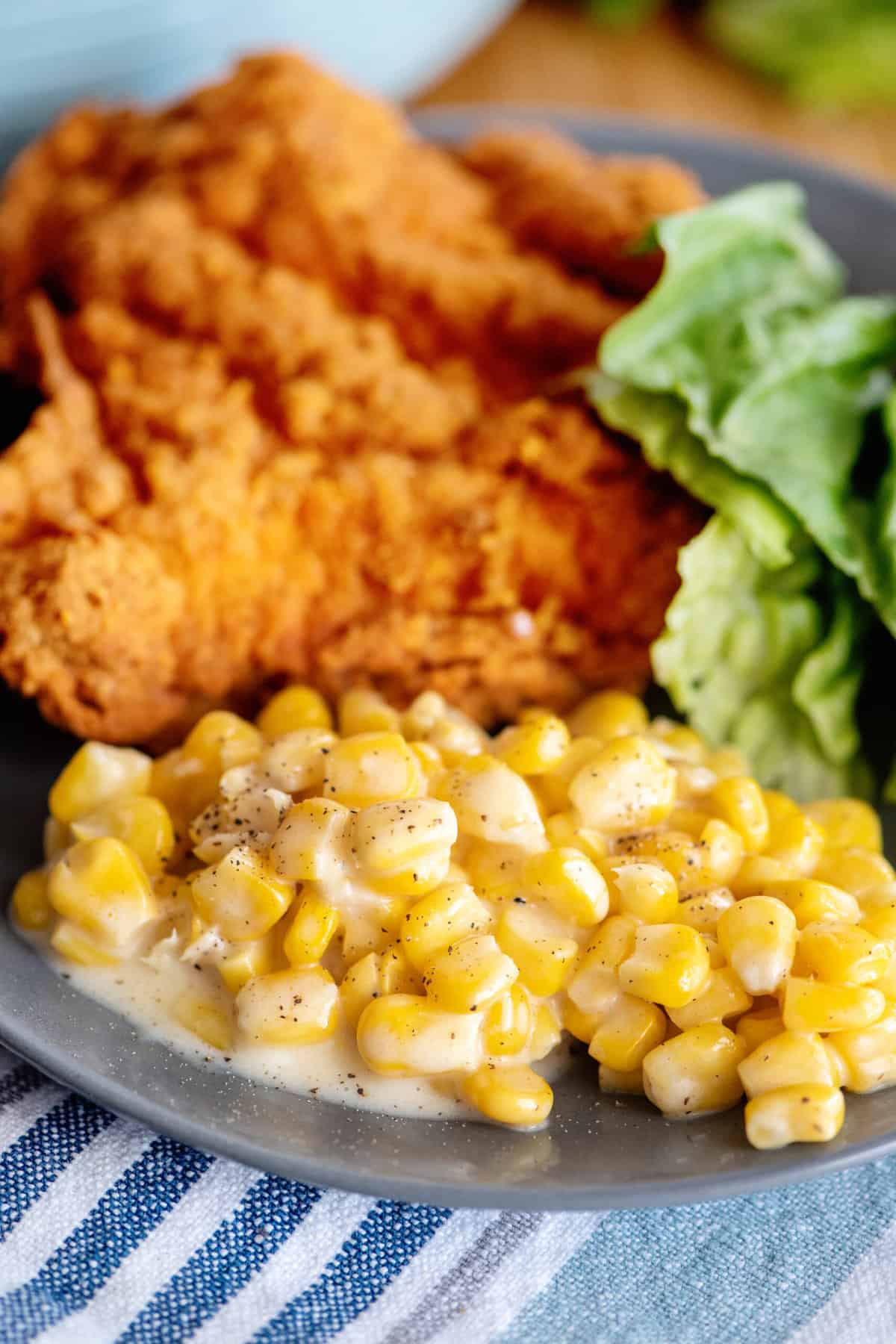 Creamed corn with fried chicken on plate.