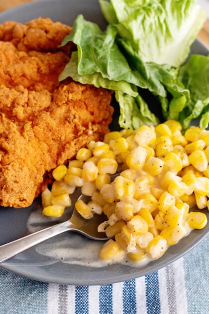 Easy creamed corn on a plate with fried chicken.