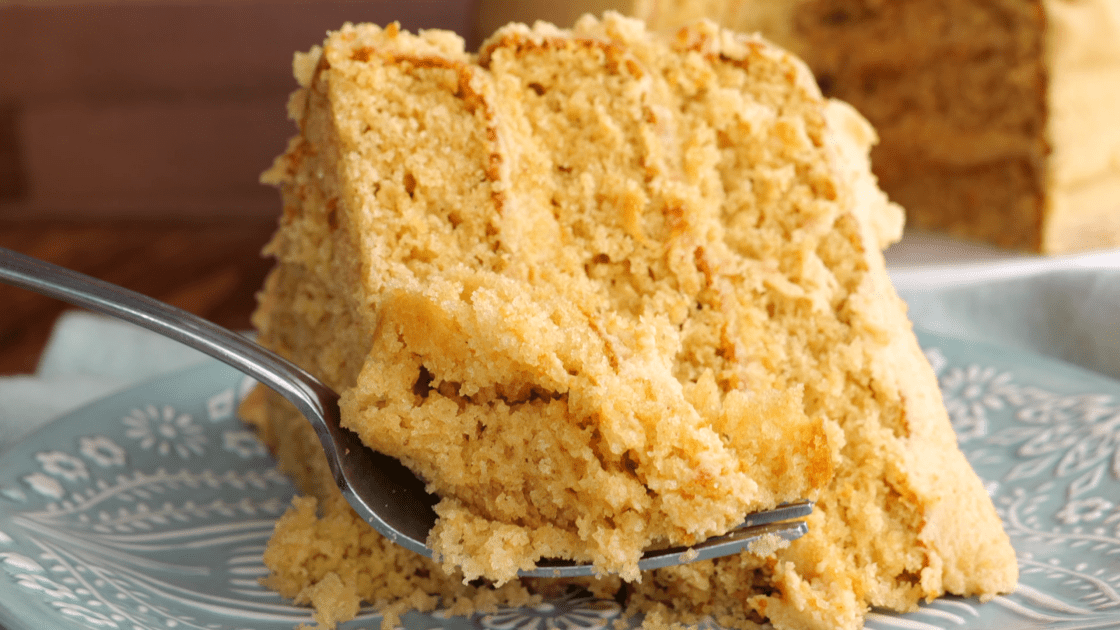 A fork with a piece of peanut butter cake with peanut butter frosting.