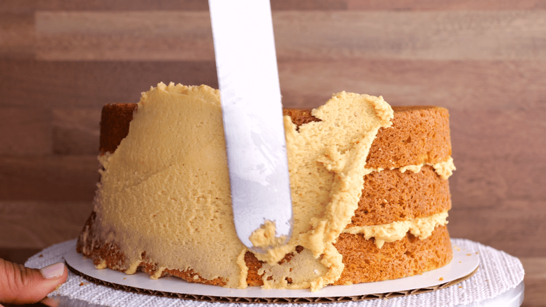 Adding peanut butter frosting to peanut butter cake.