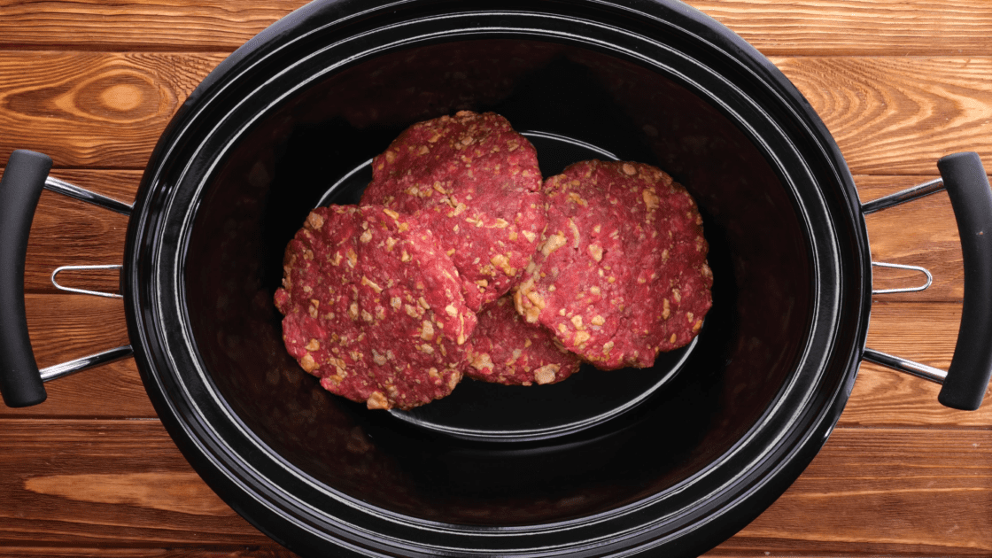 Add hamburger patties to bottom of slow cooker.
