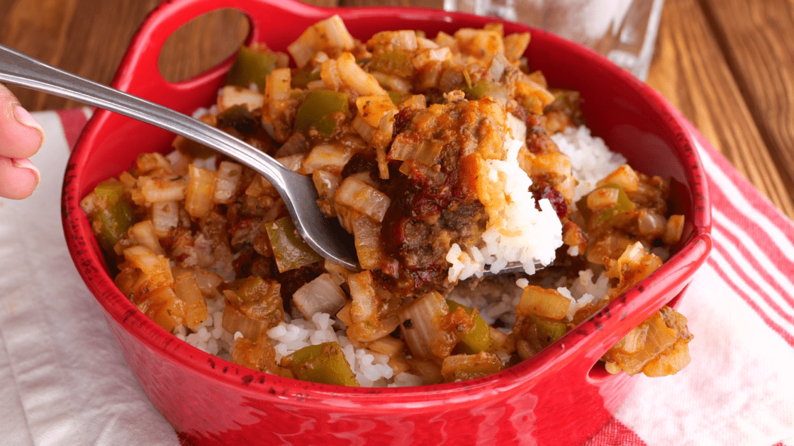Forkful of hamburger patties with gravy and rice.