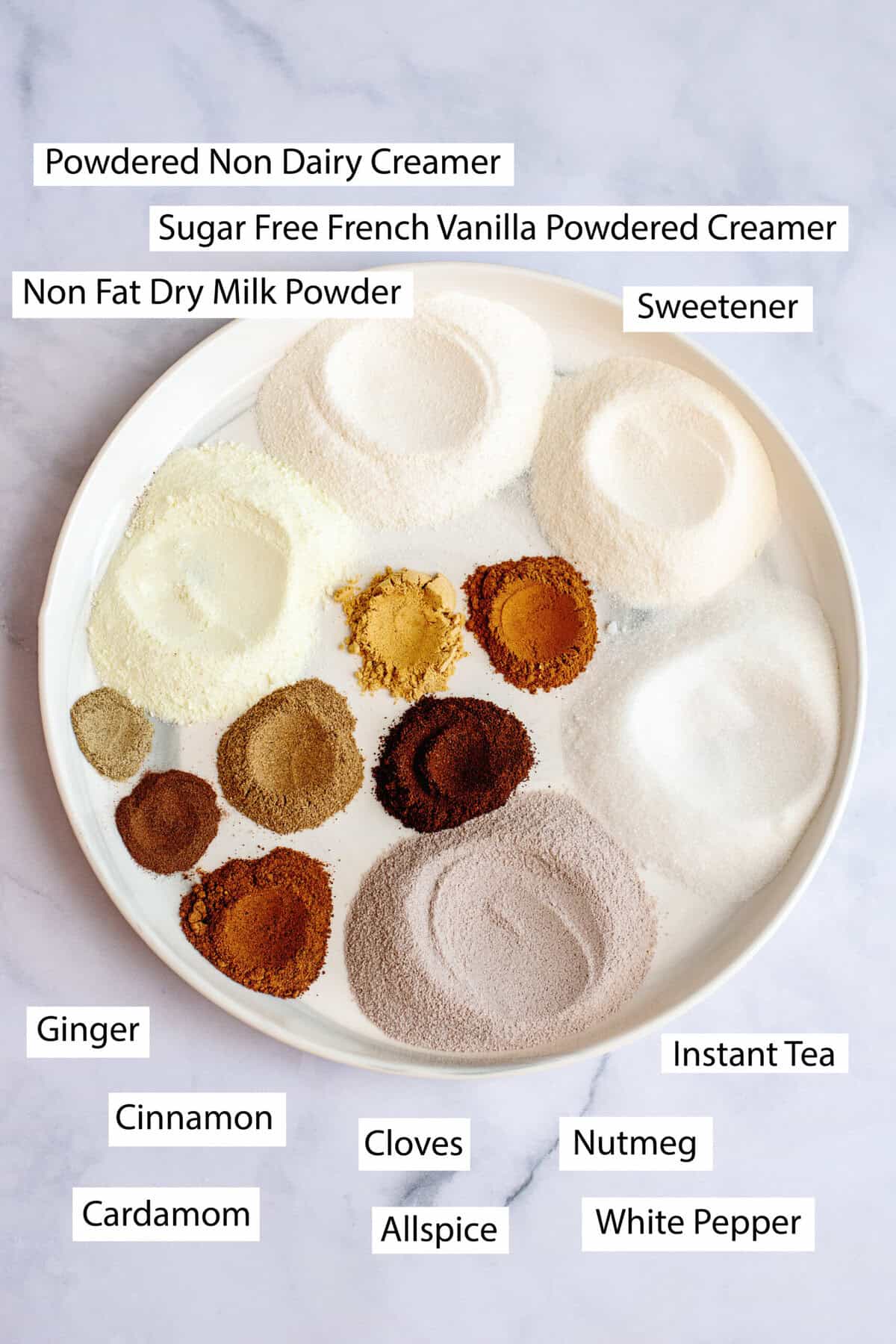 Ingredients for vanilla chai powder mix, featuring powdered creamer, milk powder, sweetener, ginger, cinnamon, cardamom, cloves, allspice, nutmeg, white pepper, and instant tea.