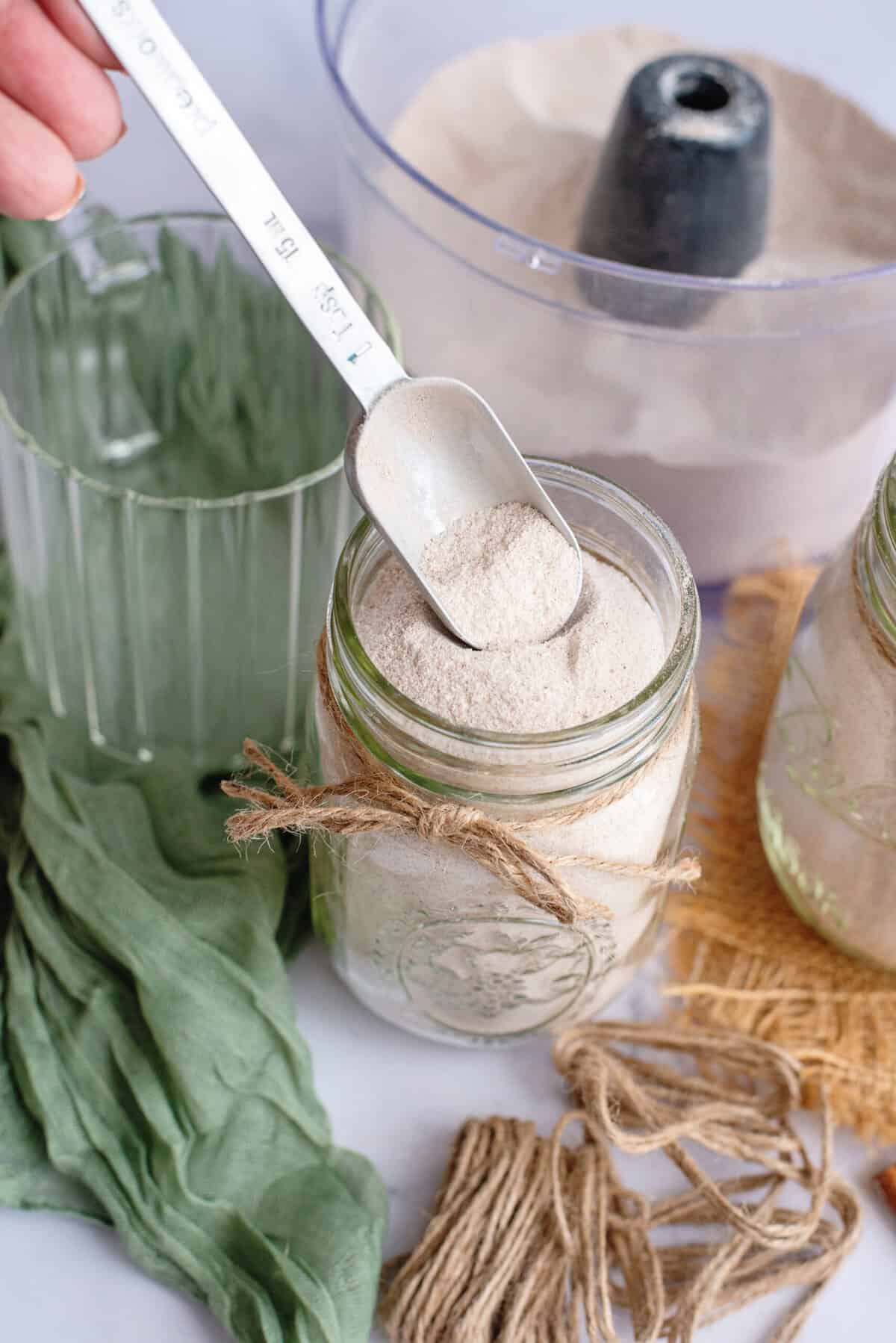 A tablespoon dipped into a mason jar of vanilla chai powder mix.