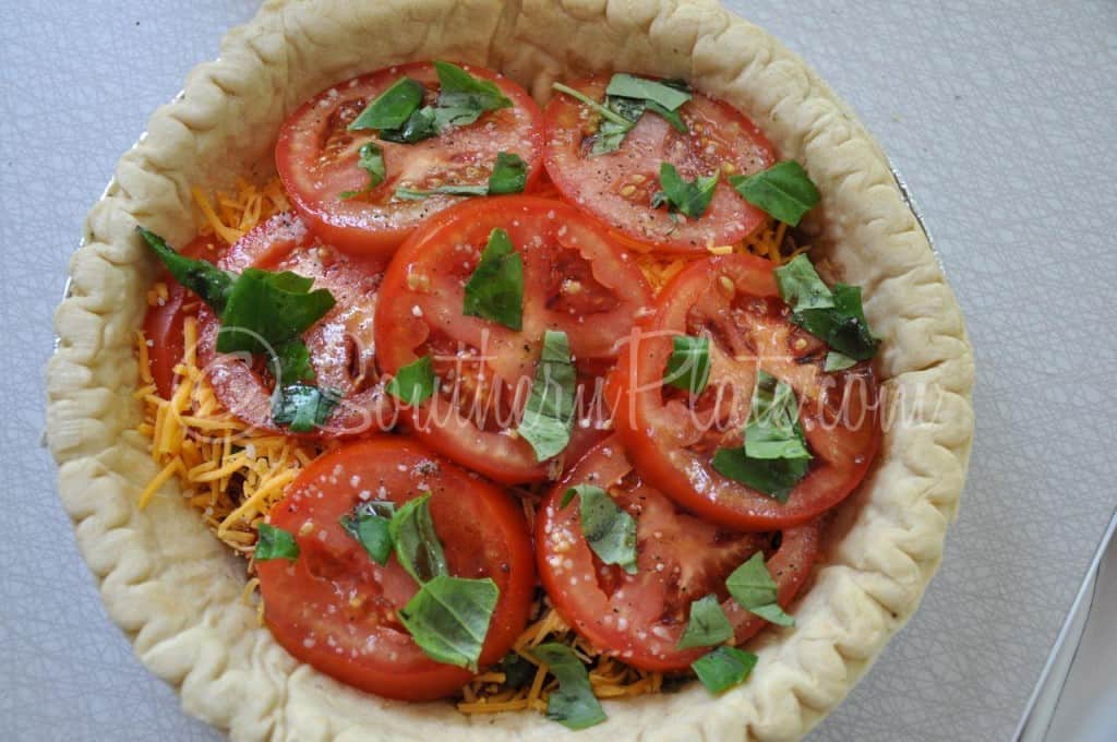 Adding tomato and basil to pie.