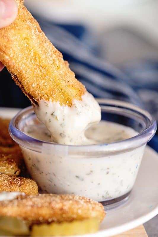 dipping fried dill pickle into ranch dressing.