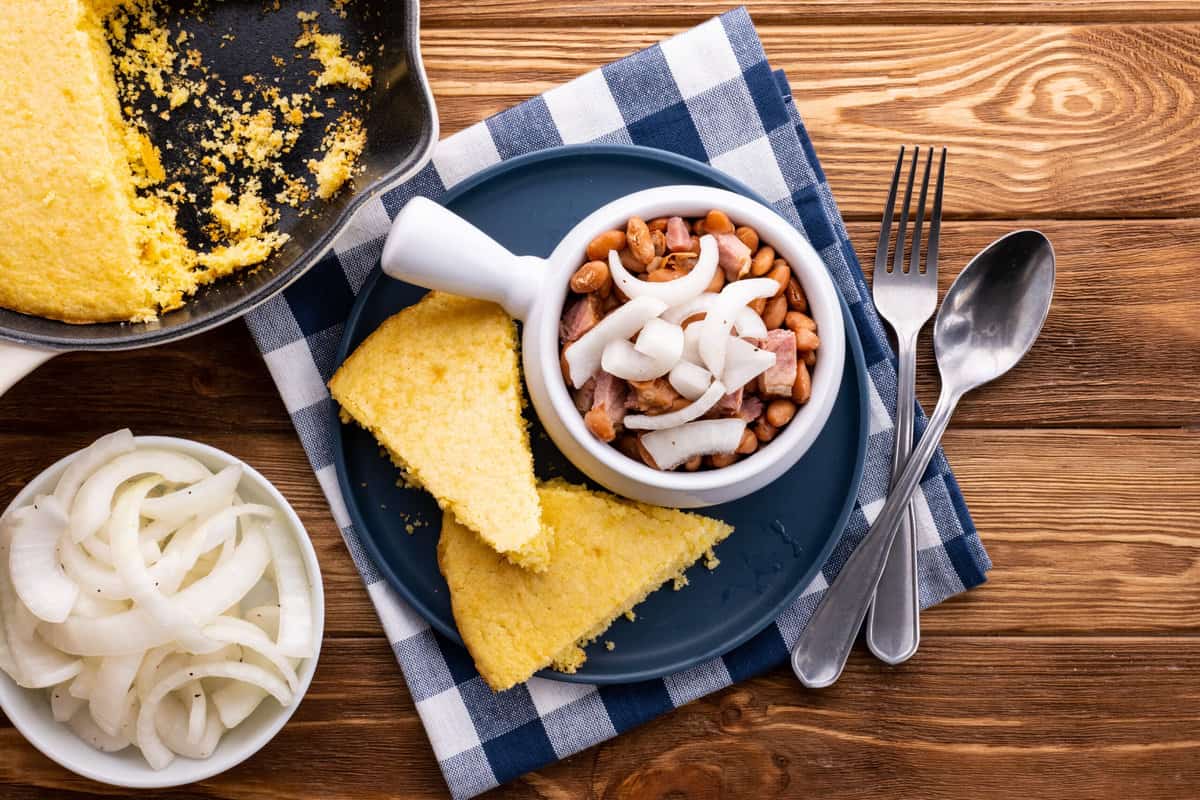 Pinto beans and ham with pickled onions on top and a side of cornbread.