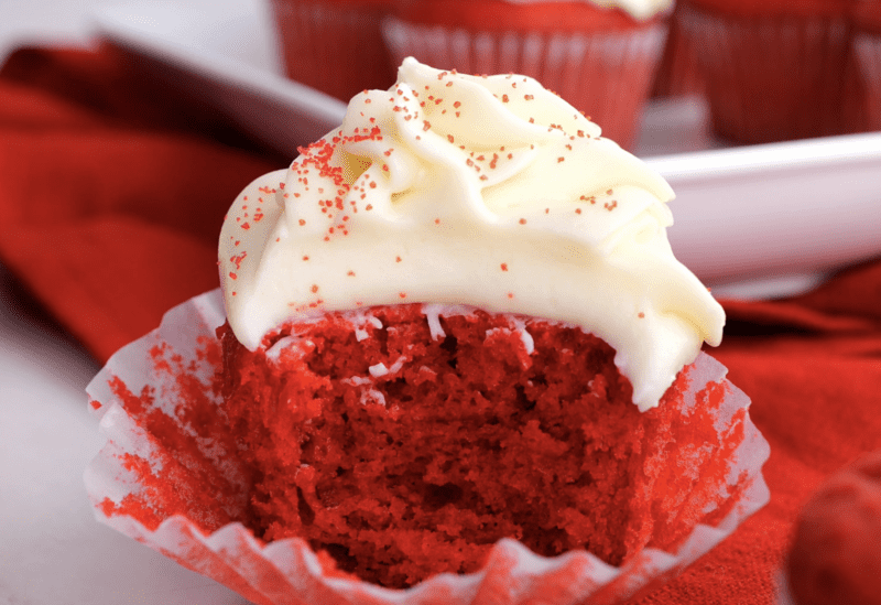 Red velvet cupcake cut in half with cream cheese frosting. 