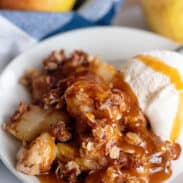 Pear crisp in bowl with scoop of vanilla ice cream.