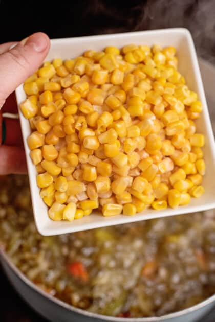 Adding corn to a pot of country chowder.
