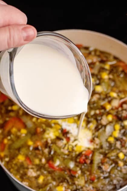 Pouring cream into a pot of country chowder.