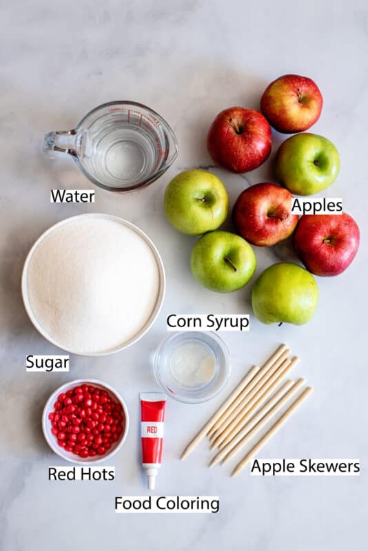 Ingredients for cinnamon candy apples: apples, sugar, corn syrup, water, Red Hot candies, red food coloring, and wooden sticks