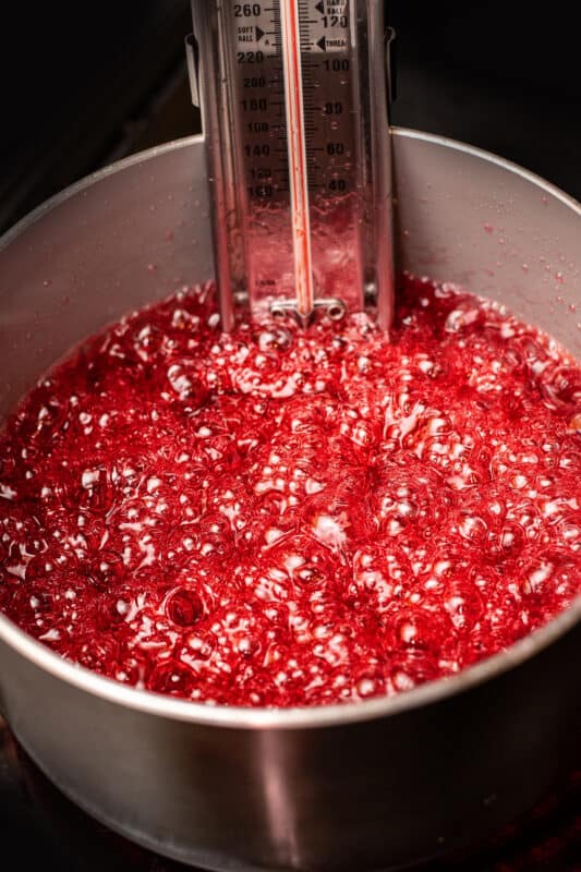 Candy syrup boiling with a candy thermometer clipped to the pan