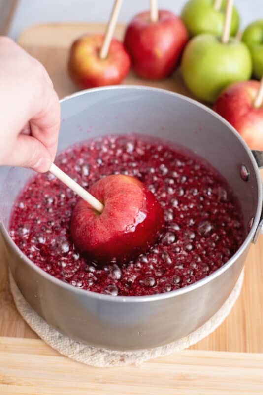 Dipping an apple into hot red candy coating